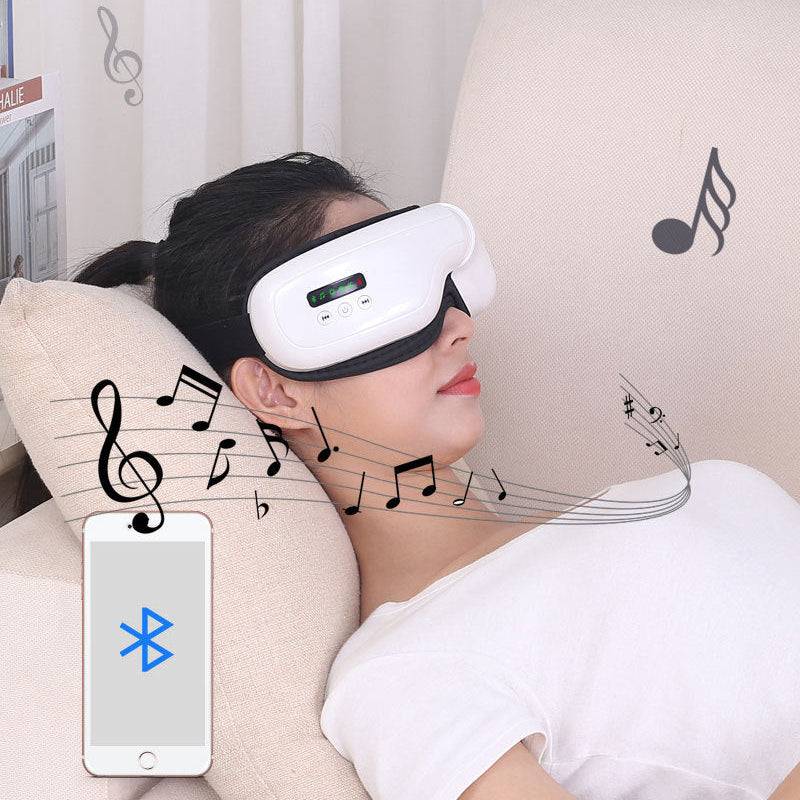 A woman reclines on a beige sofa wearing a white and black eye massager headset. The image includes music note graphics, a smartphone showing a Bluetooth icon, and decorative musical staff lines against a light curtain background.