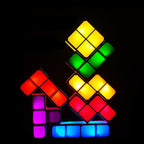 A set of glowing block lights arranged in house shapes against a black background. The lights display multiple colors, including yellow, green, red, purple, and blue.